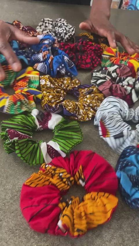 video of hands gathering together various colourful african print hair ties scrunchies