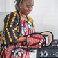 Light pink african print oven gloves and apron set worn by a happy black woman