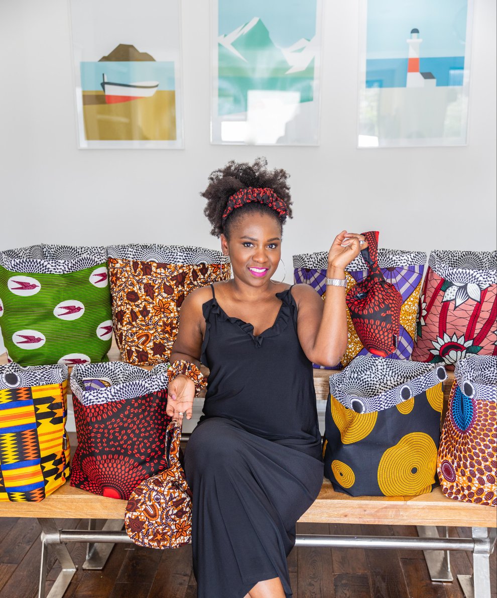 Black female founder surrounded by eight ankara african print storage baskets in lots of colors